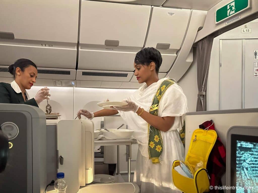 Ethiopian Airlines Airbus A350-900 Business Class flight attendent in traditional dress serving Ethiopian food