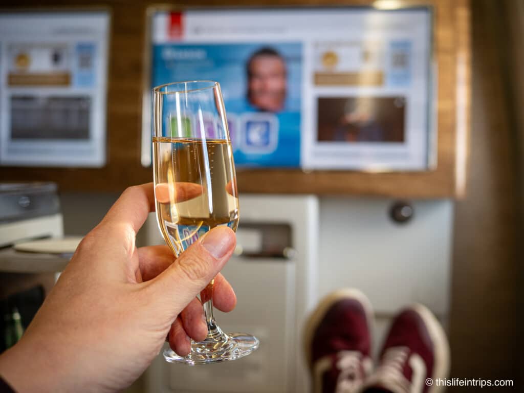 Hand holding up glass of champagne on an Emirates 777 business class flight