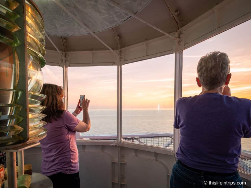 women taking sunset photos at the top of the West Point Lighthouse PEI