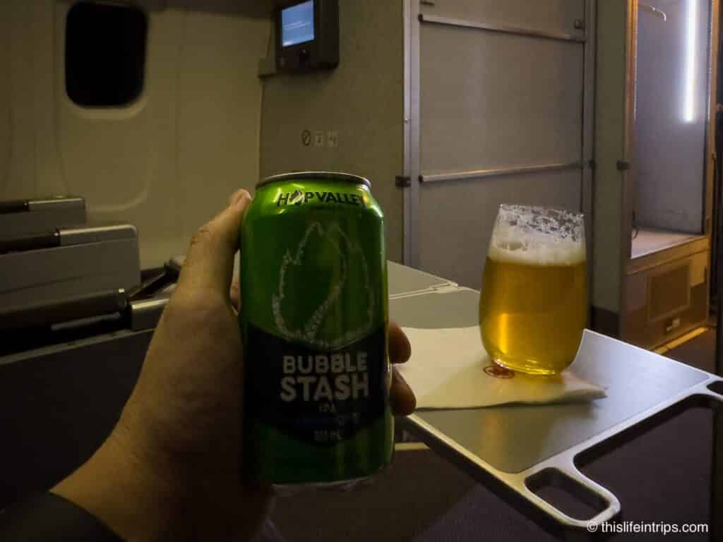 Hand holding a Hop Valley beer in Air Canada CRJ 900 business class