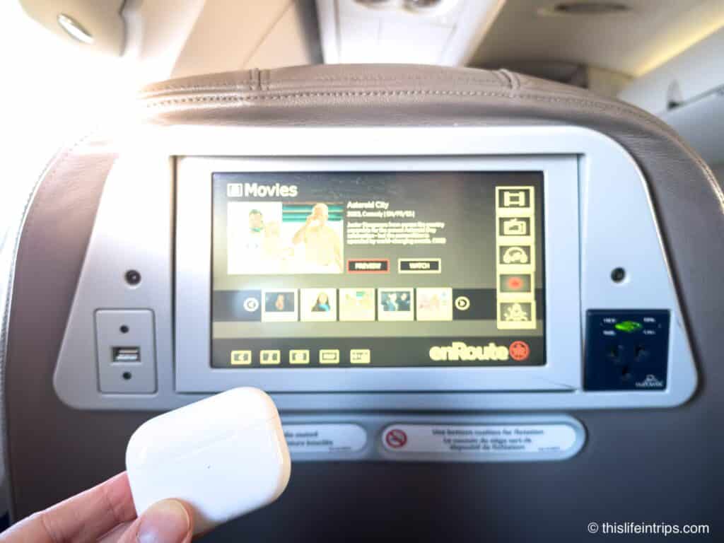 holding up airpods on a plane in front of IFE system