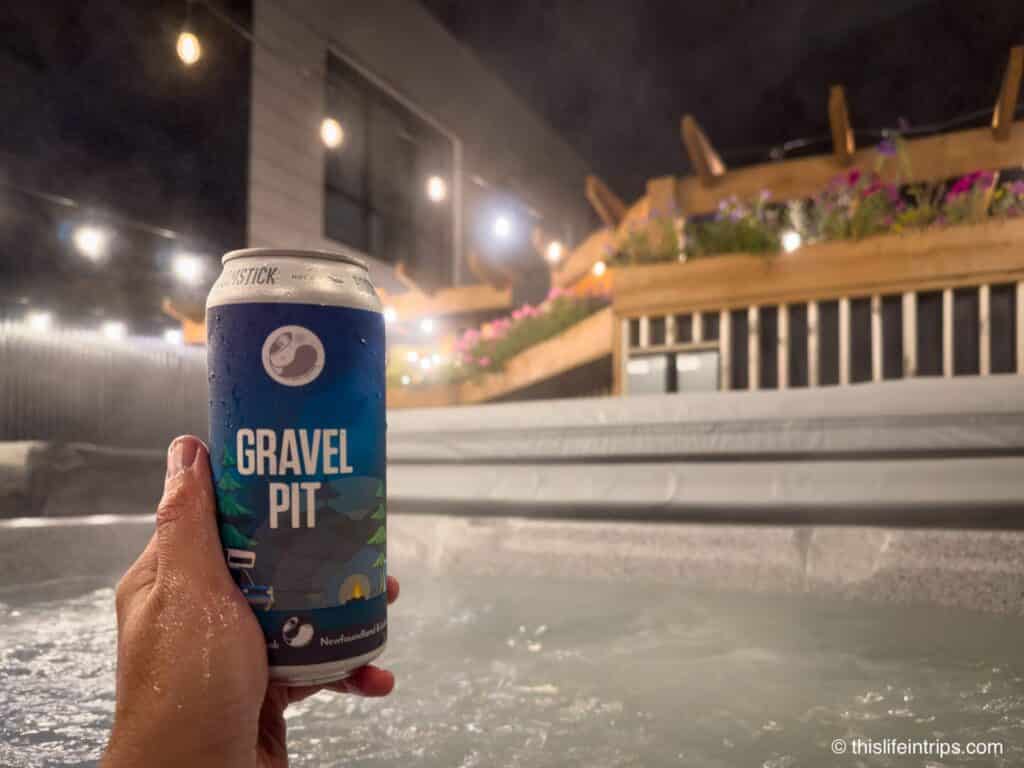 hand holding up a Gravel Pit beer in a hot tub at the Hew and Draw Hotel in Corner Brook Newfoundland