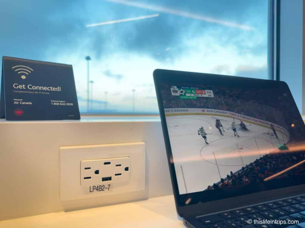 Laptop playing a hockey game next to a power plug at the San Francisco Air Canada Lounge