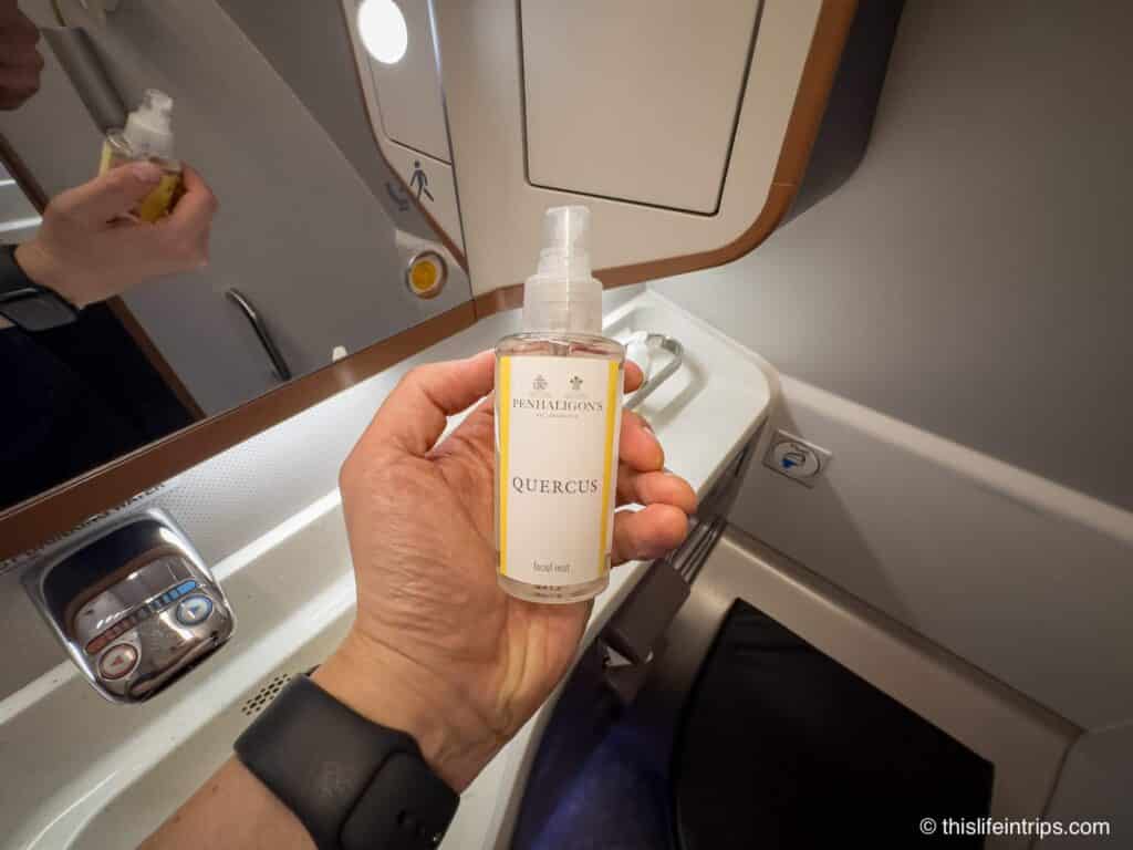 hand holding up facial mist inside Singapore Airlines a380 Business Class lavatory