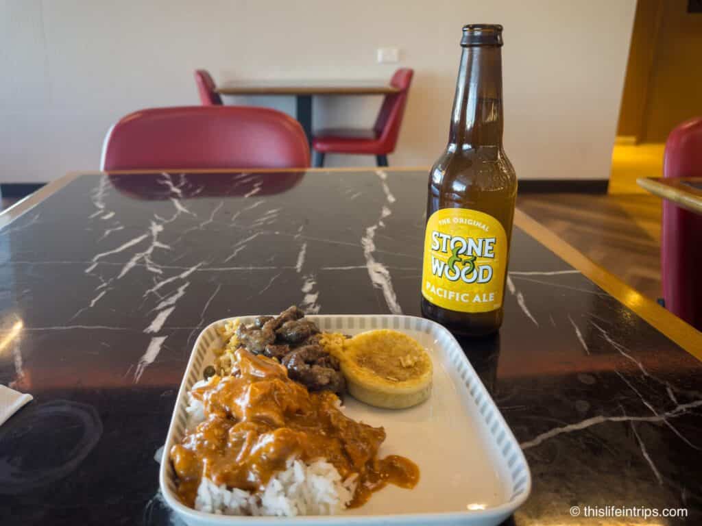 Plate of butter chicken and a Stone Wood Pacific Ale at the Singapore Airlines lounge in Sydney