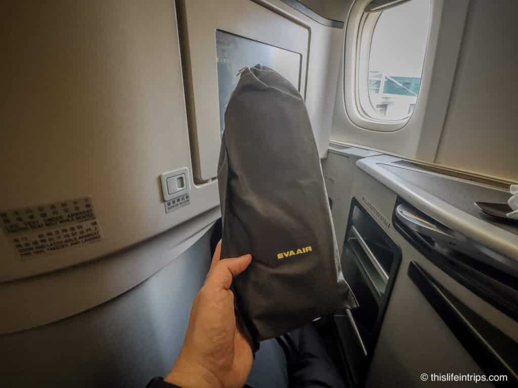 Hand holding up EVA Air business class slippers in business class seat