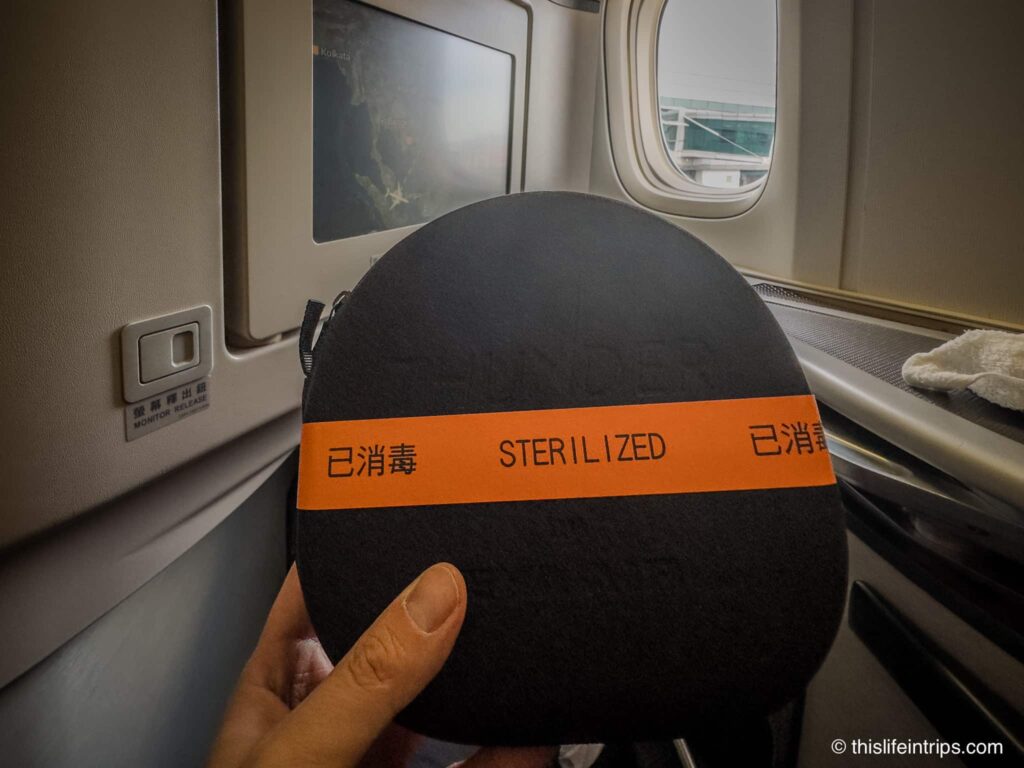 Hand holding up EVA Air business headphones in business class seat