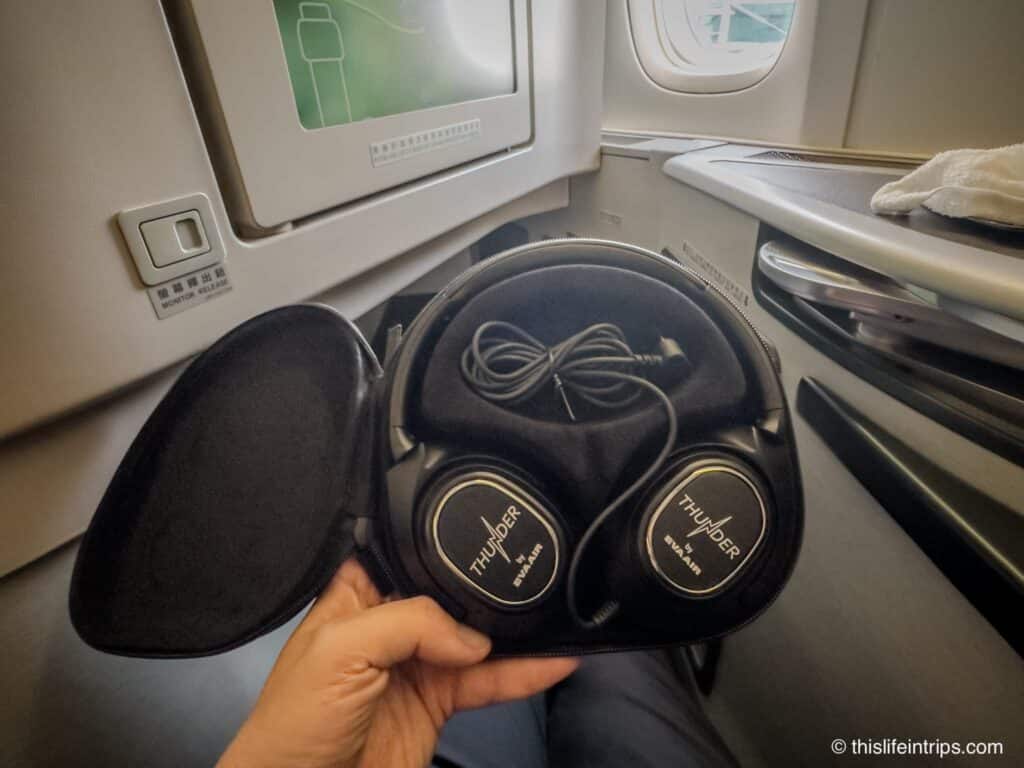 Hand holding up EVA Air business headphones in business class seat