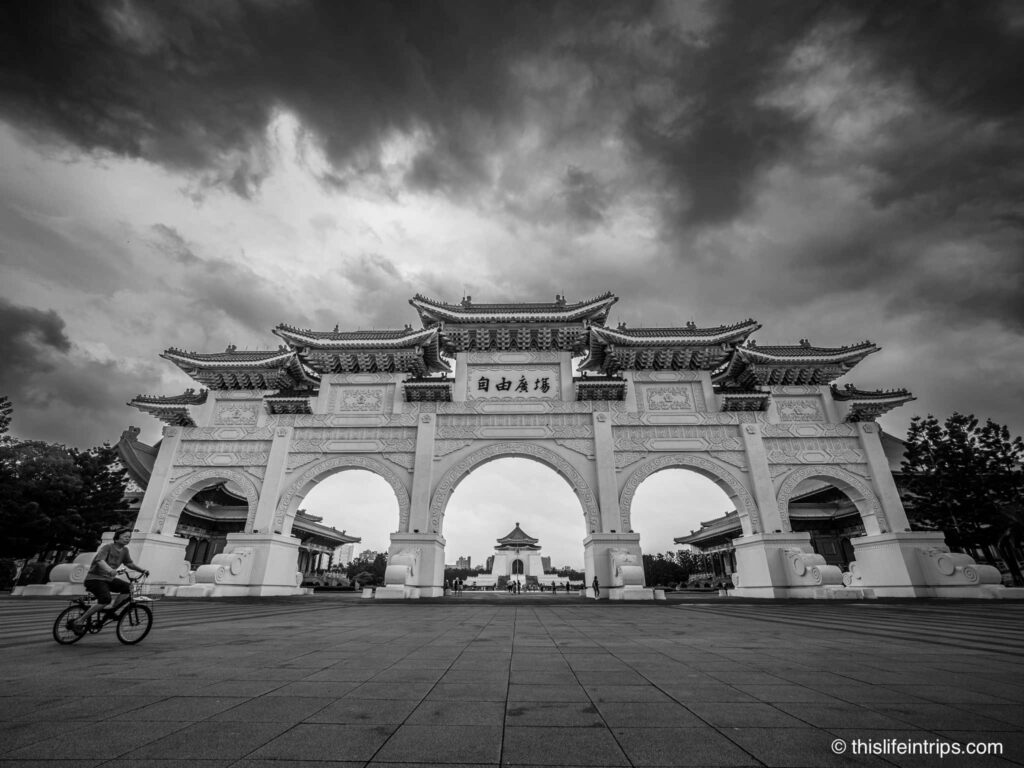 Main Gate of National Chiang Kai-shek Memorial Hall in black and white with women on bike in front