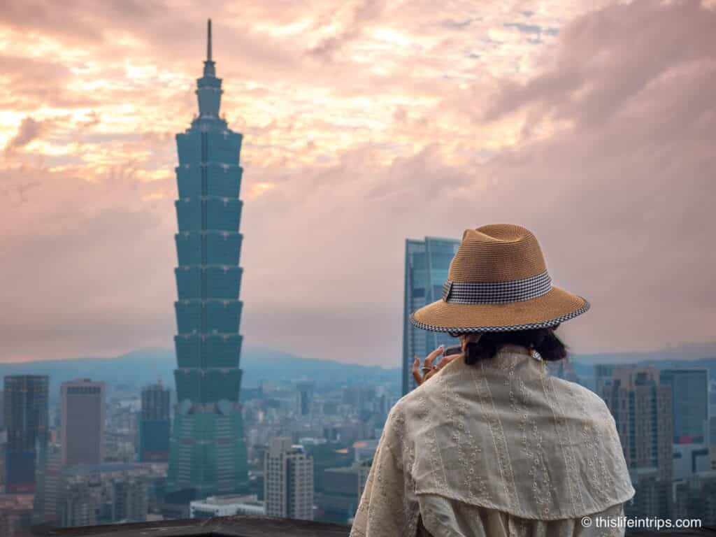 Women in a hat with Taipei 101 and city skyline as seen from Elephant Mountain