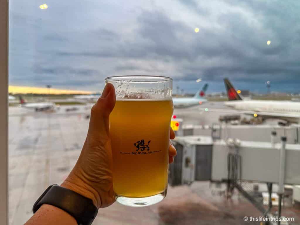 Hand holding beer overlooking tarmac at YUL airport in Montreal