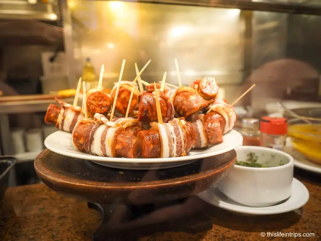 A plate of chorizo wrapped in bacon inside a send Sebastian Pintxos bar