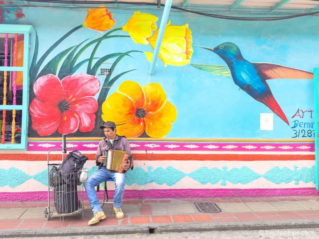 Man playing accordion in front of colourful mural in Guatape, Colombia