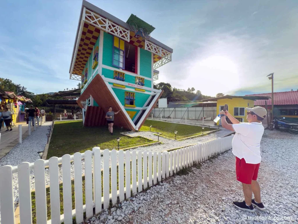 man taking photo of upside down house on a Guatape day tour